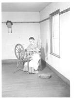 SA0023 - Sarah Collins was from the South Family.  Photo shows her using a spinning wheel near a window.
